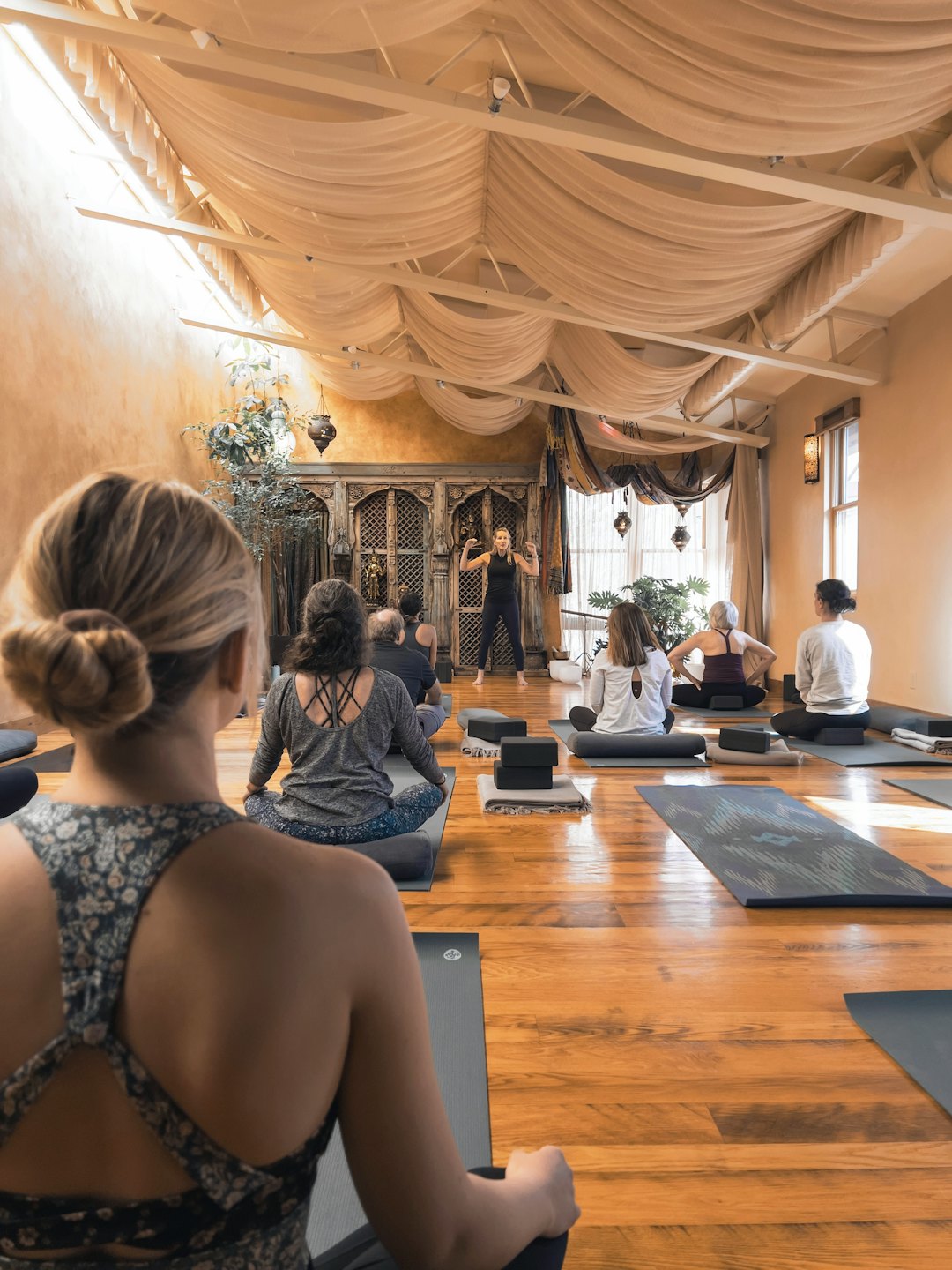 Yoga instructor leads a class in a wooden studio.
